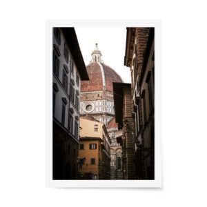 Photograph of Florence’s Duomo seen through a narrow street with historic buildings, featuring warm tones and architectural details.