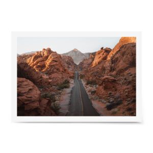 Fine art photograph of an empty desert highway cutting through red sandstone formations in Nevada’s Valley of Fire at golden hour.
