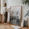 Large framed Brooklyn Bridge abstract print leaning against a white wall in a studio, styled with rolled prints and hardwood floors.