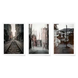 Modern gallery wall set featuring a city double exposure, a narrow train track street scene, and a decaying building with painted eyes.