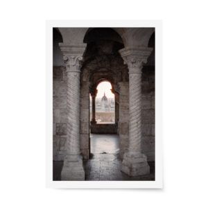 Stone archway framing the Hungarian Parliament at sunset, fine art photograph with warm tones and architectural detail.